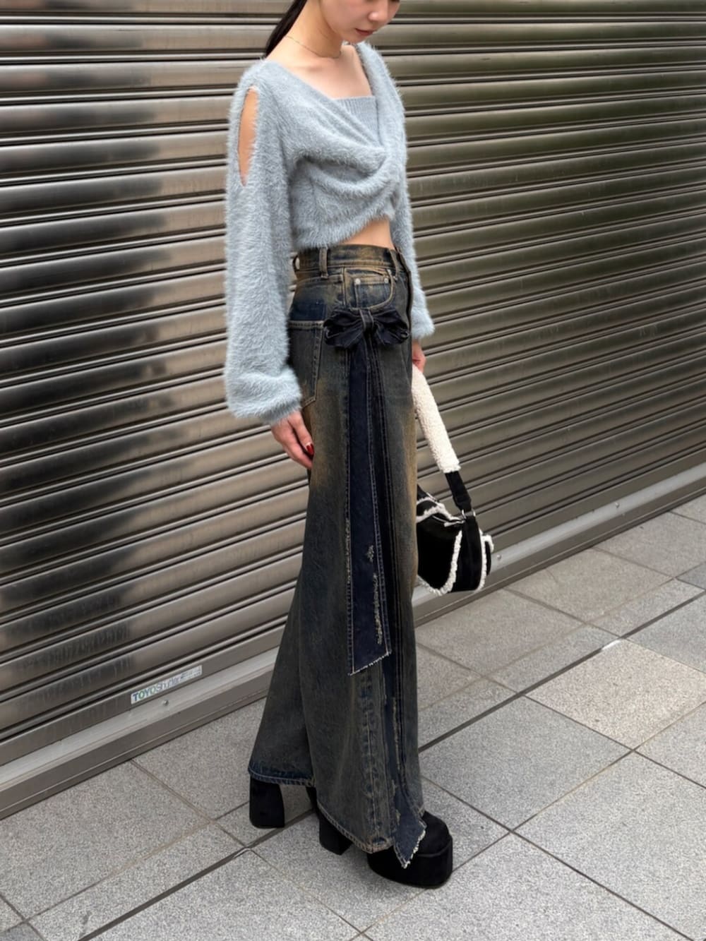 ブルー系のニット/セーター、ブルー系のデニムパンツ、ブラック系のハンドバッグを着用したレディースの秋コーディネートの2枚目の写真