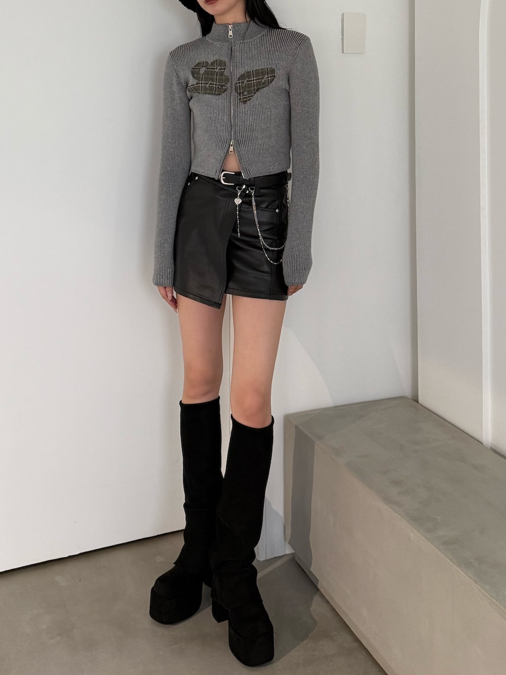 ブラック系のブーツ、ブラック系のスカート、グレー系のニット/セーターを着用したレディースの秋コーディネートの2枚目の写真