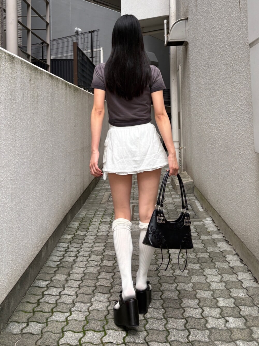 ブラック系のショルダーバッグ、ブラック系のサンダル、ブラック系のTシャツ/カットソーを着用したレディースの夏コーディネートの3枚目の写真