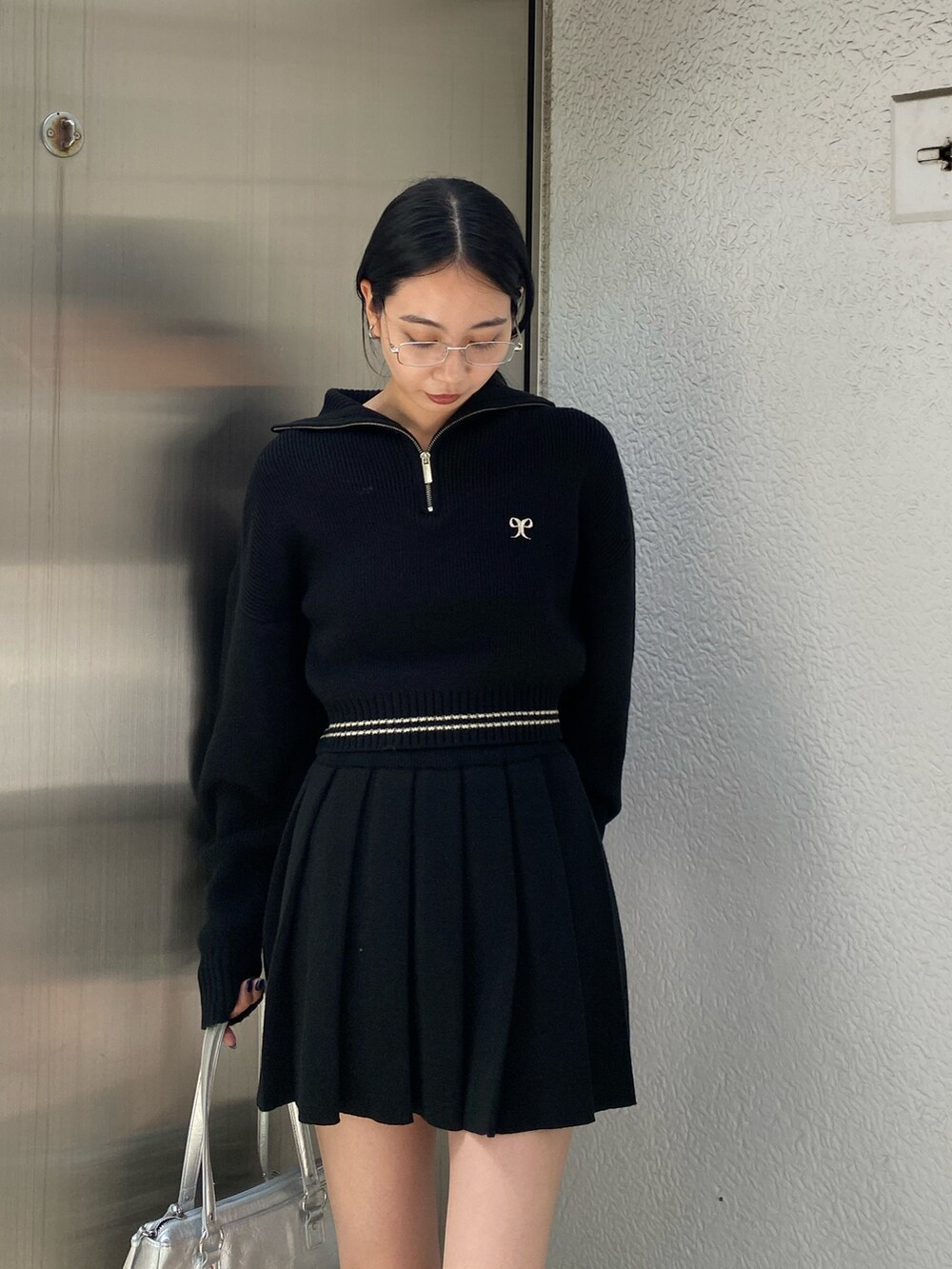 ホワイト系のブーツ、ブラック系のニット/セーター、ブラック系のスカートを着用したレディースの秋コーディネートの3枚目の写真