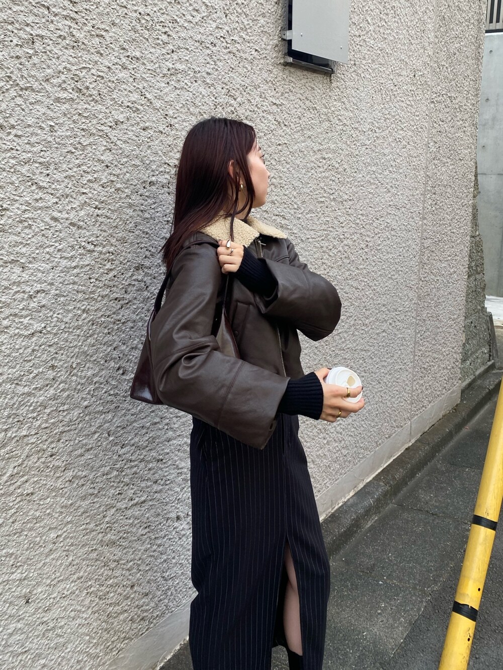 ブラック系のスカート、ブラウン系のブルゾン、ブラック系のブーツを着用したレディースの秋コーディネートの3枚目の写真