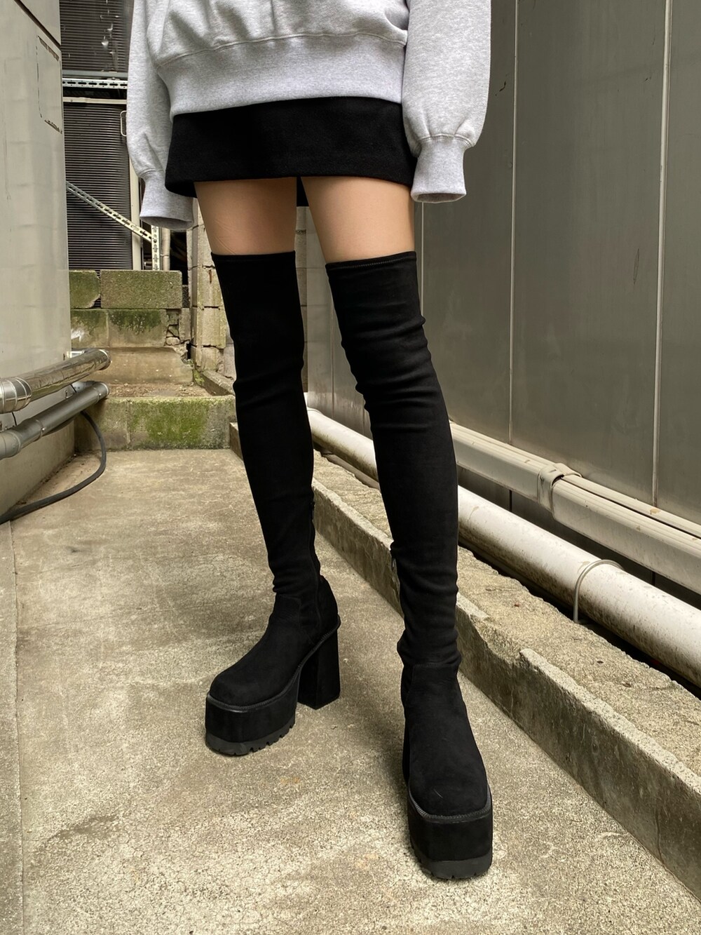 ブラック系のハンドバッグ、ブラック系のブーツ、グレー系のスウェットを着用したレディースの夏コーディネートの5枚目の写真