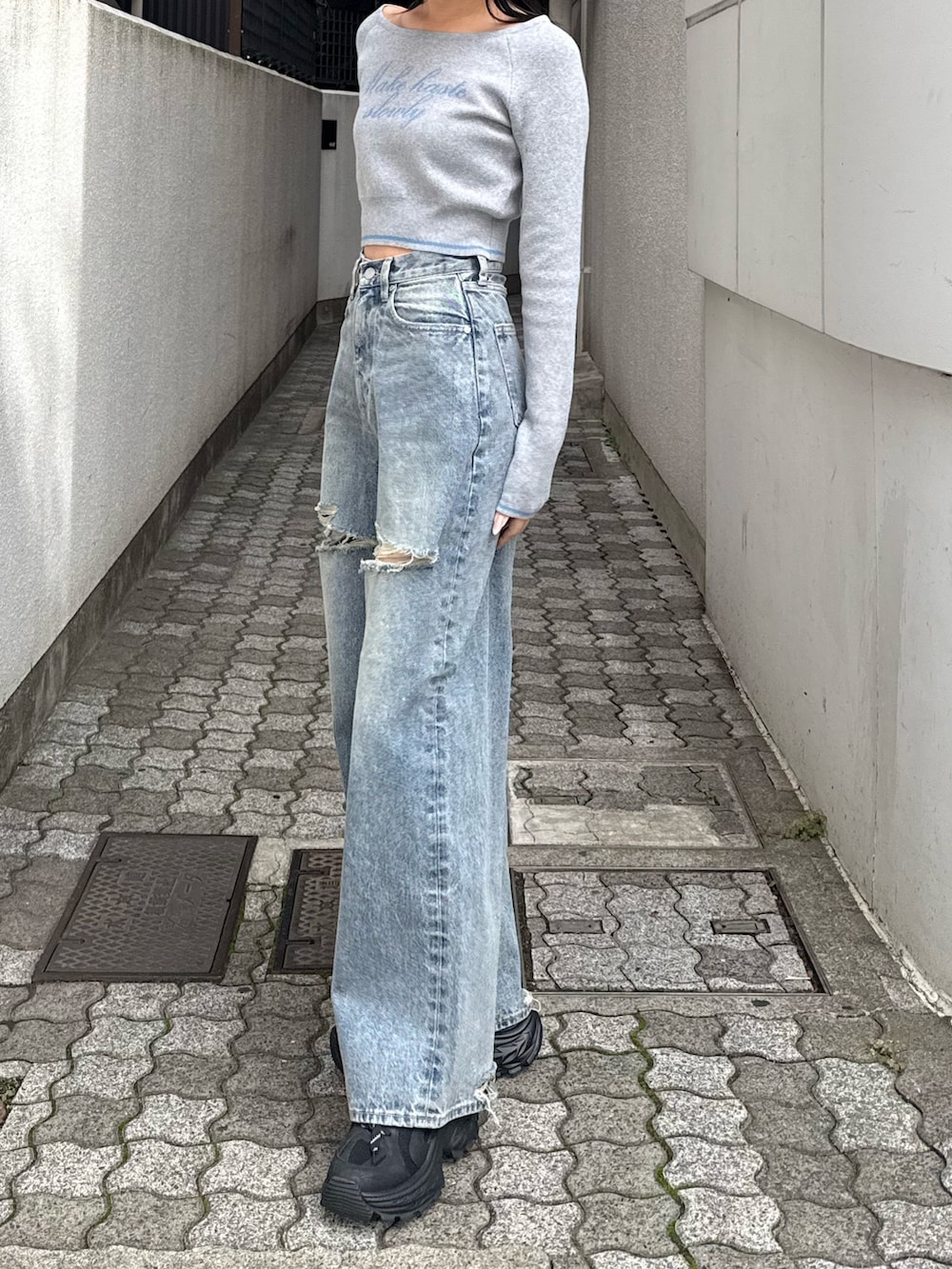 グレー系のニット/セーター、ブルー系のデニムパンツ、ブラック系のスニーカーを着用したレディースの秋コーディネートの2枚目の写真