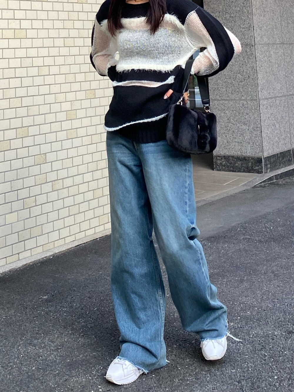 ブラック系のハンドバッグ、ブラック系のニット/セーター、ブルー系のデニムパンツを着用したレディースの秋コーディネートの3枚目の写真