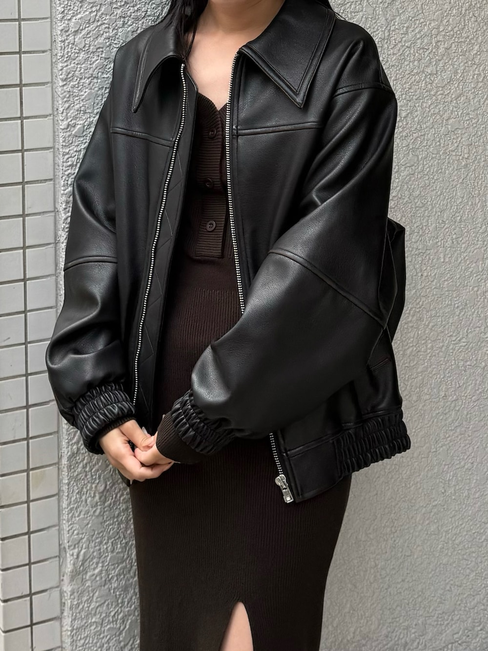 ブラック系のブルゾン、ブラウン系のワンピース、ホワイト系のブーツを着用したレディースの冬コーディネートの2枚目の写真