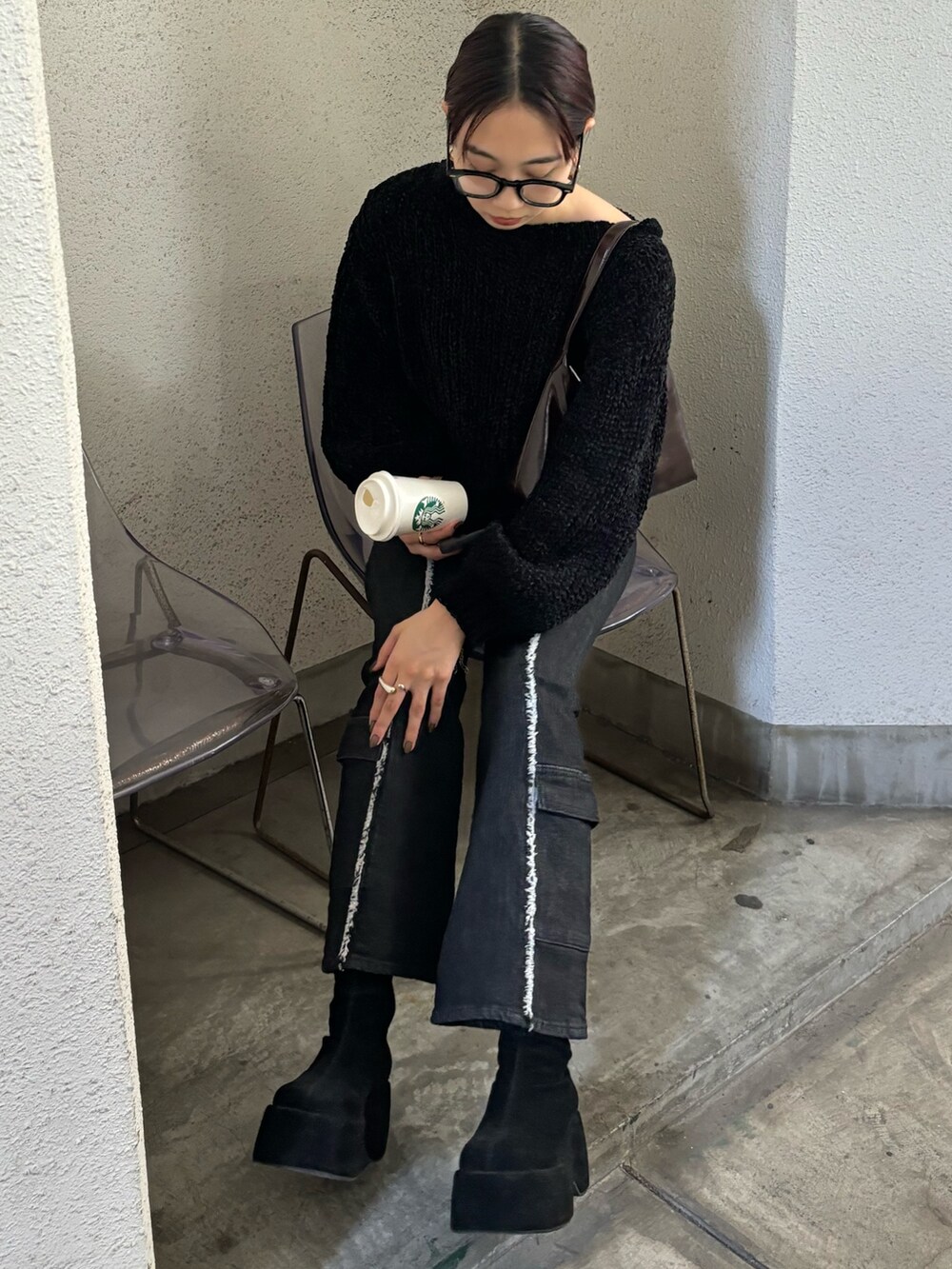 ブラック系のニット/セーター、ブルー系のデニムパンツ、ブラック系のブーツを着用したレディースの秋コーディネートの2枚目の写真