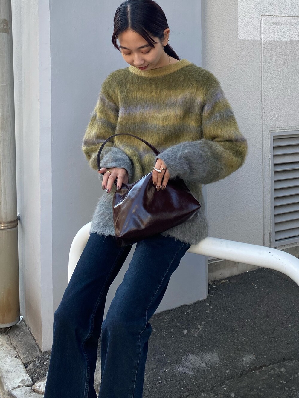 グリーン系のニット/セーター、ブルー系のデニムパンツを着用したレディースの秋コーディネートの2枚目の写真