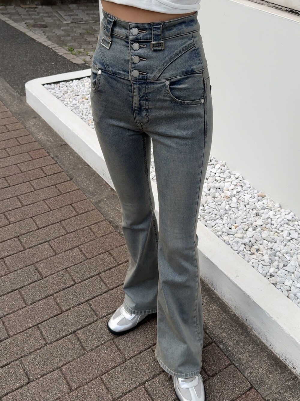 ブルー系のデニムパンツ、ホワイト系のTシャツ/カットソー、シルバー系のスニーカーを着用したレディースの春コーディネートの2枚目の写真