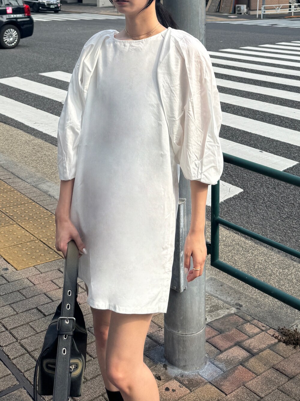 ホワイト系のワンピース、ブラック系のブーツ、ブラック系のハンドバッグを着用したレディースの夏コーディネートの3枚目の写真