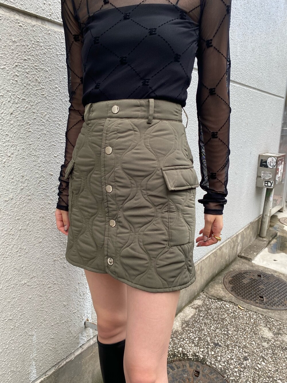 ブラック系のTシャツ/カットソー、グリーン系のスカート、ブラック系のブーツを着用したレディースの秋コーディネートの4枚目の写真