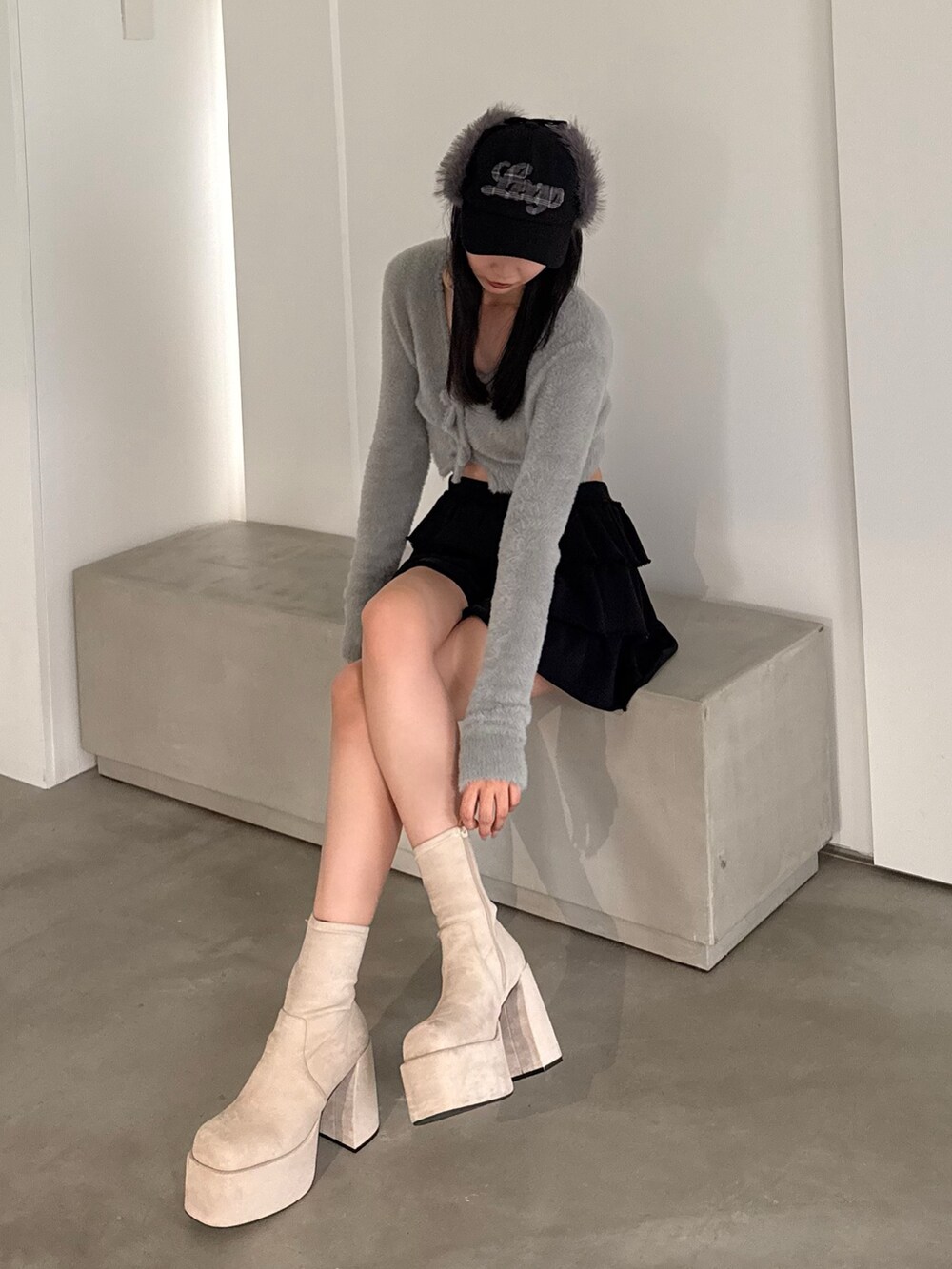 ホワイト系のブーツ、ブラック系のスカート、グレー系のニット/セーターを着用したレディースの秋コーディネートの2枚目の写真