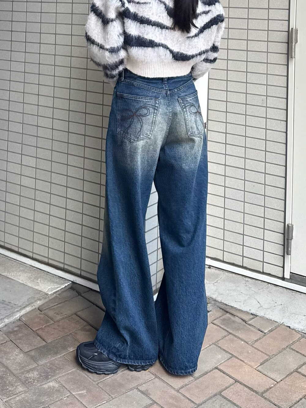 ブルー系のデニムパンツ、ホワイト系のニット/セーターを着用したレディースの秋コーディネートの2枚目の写真