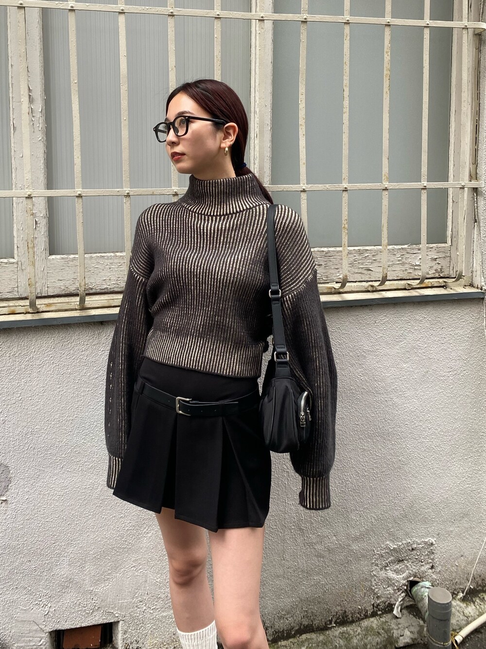 ブラック系のハンドバッグ、ブラック系のニット/セーター、ブラック系のスカートを着用したレディースの秋コーディネートの3枚目の写真