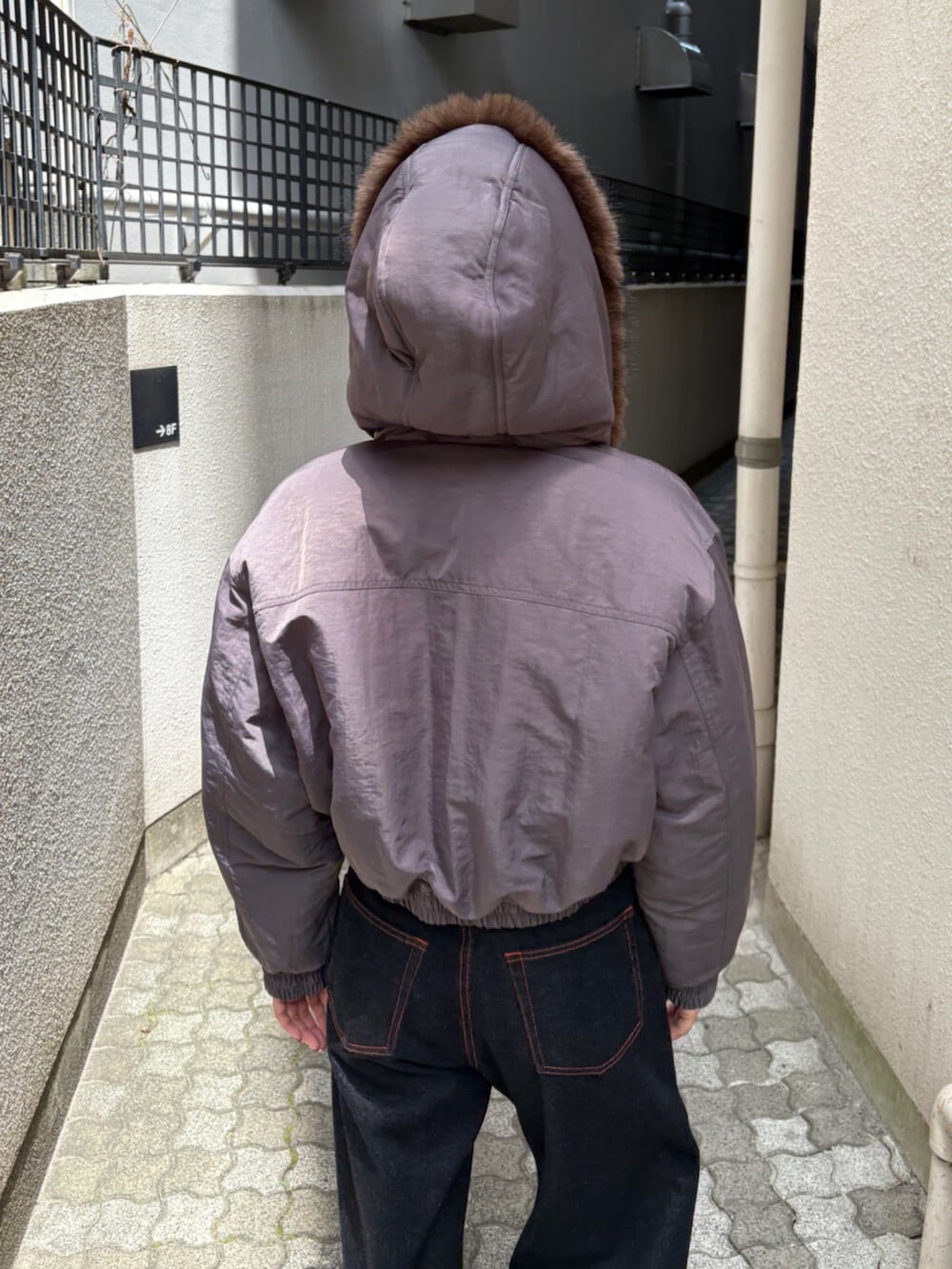 ブルー系のデニムパンツ、グレー系のブルゾン、ブラック系のブーツを着用したレディースの秋コーディネートの5枚目の写真