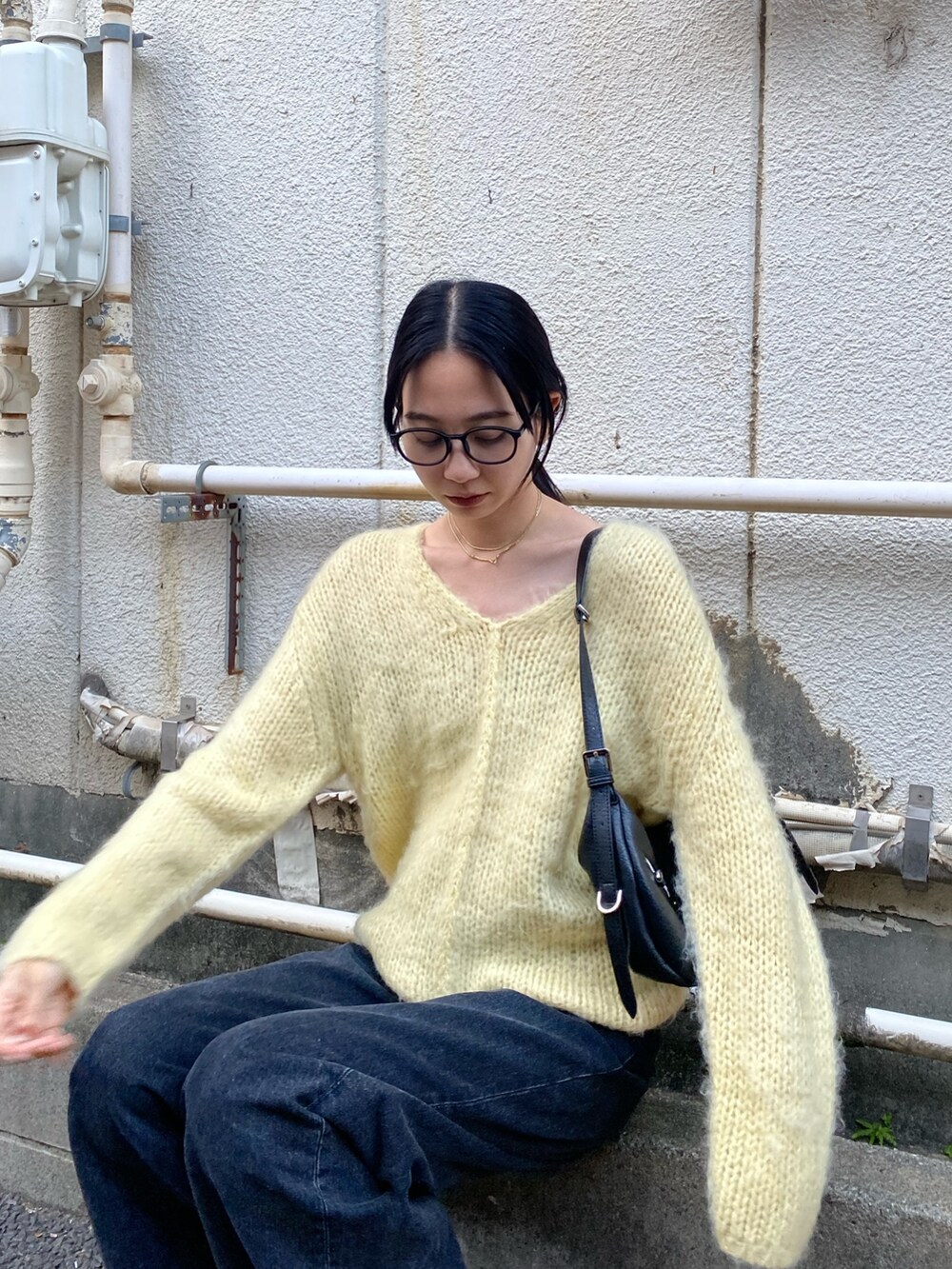 イエロー系のニット/セーター、ブラック系のハンドバッグを着用したレディースの冬コーディネートの2枚目の写真