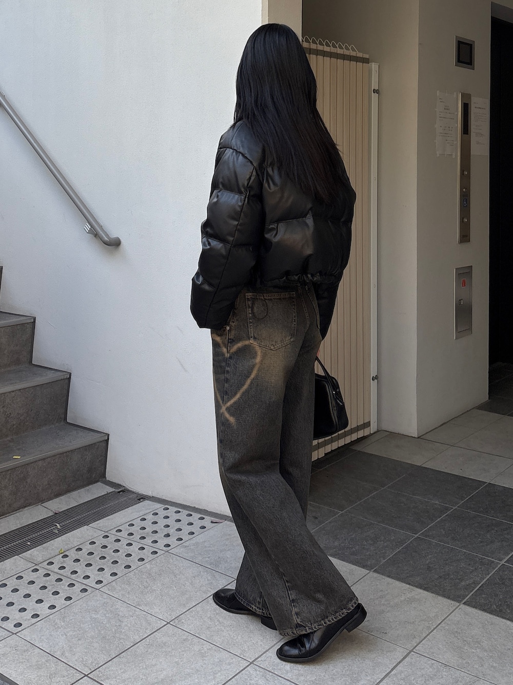 ブルー系のデニムパンツ、ブラック系のダウンジャケット/コートを着用したレディースの冬コーディネートの2枚目の写真