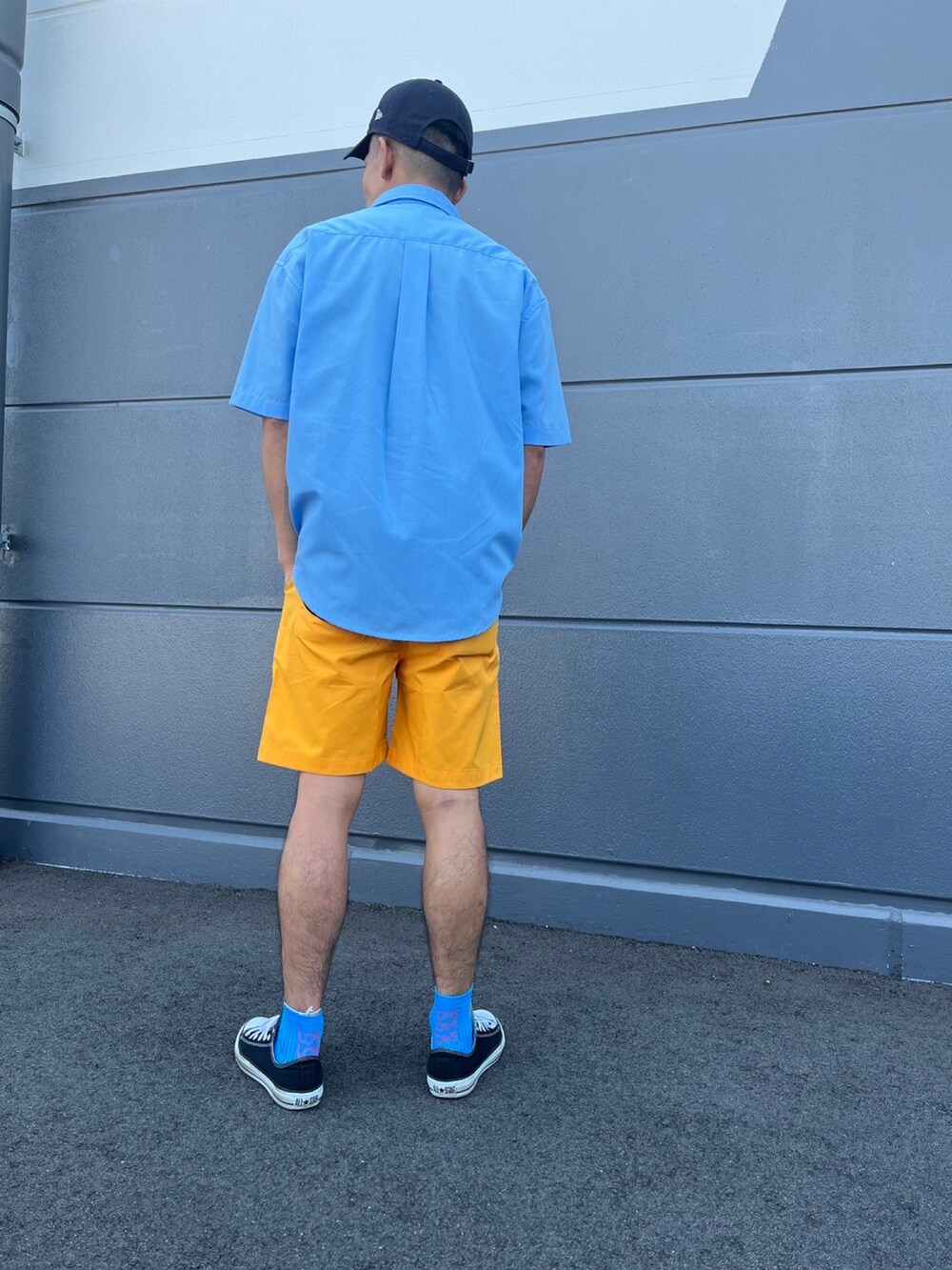ブルー系のシャツ/ブラウス、オレンジ系のパンツ、ブラック系のスニーカーを着用したメンズの夏コーディネートの2枚目の写真