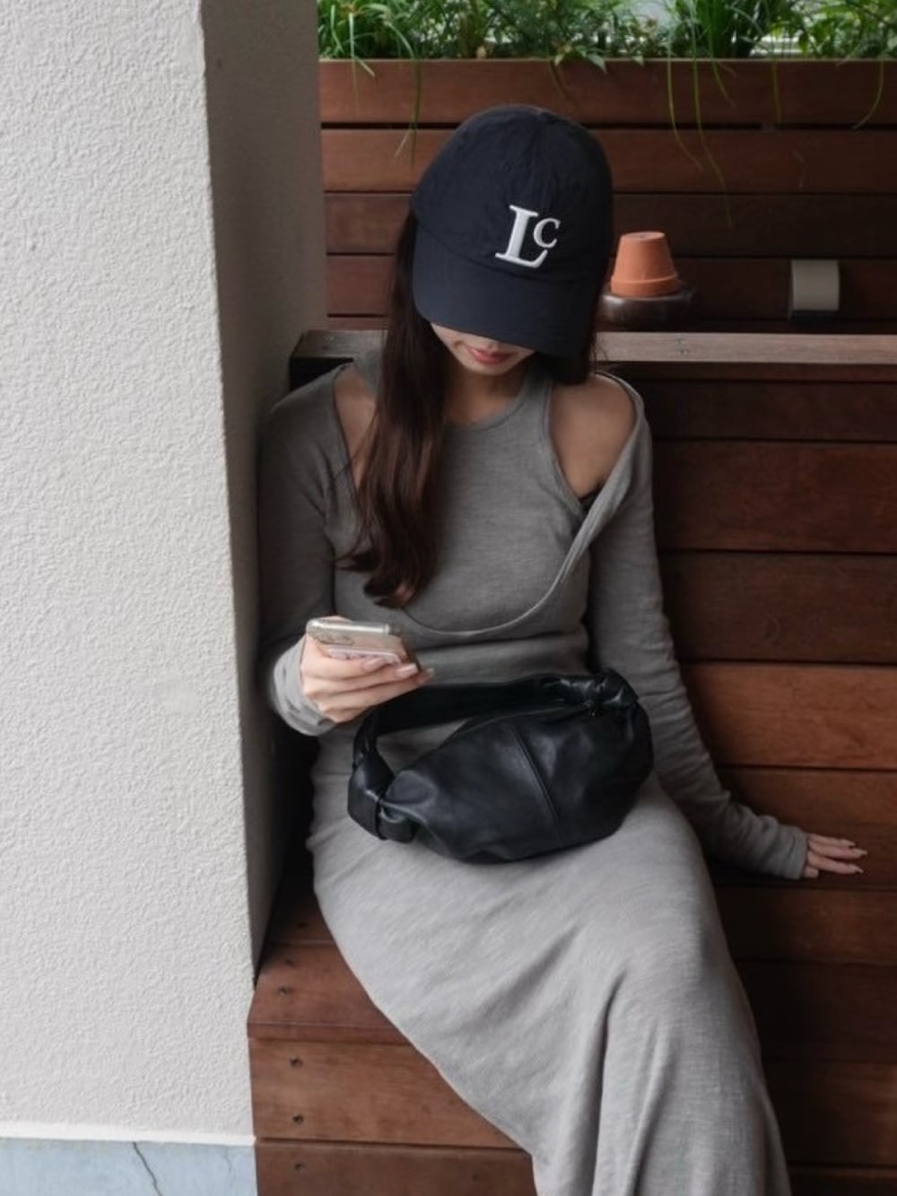 グレー系のワンピース、ブラック系のスニーカー、ブラック系のハンドバッグを着用したレディースの秋コーディネートの2枚目の写真