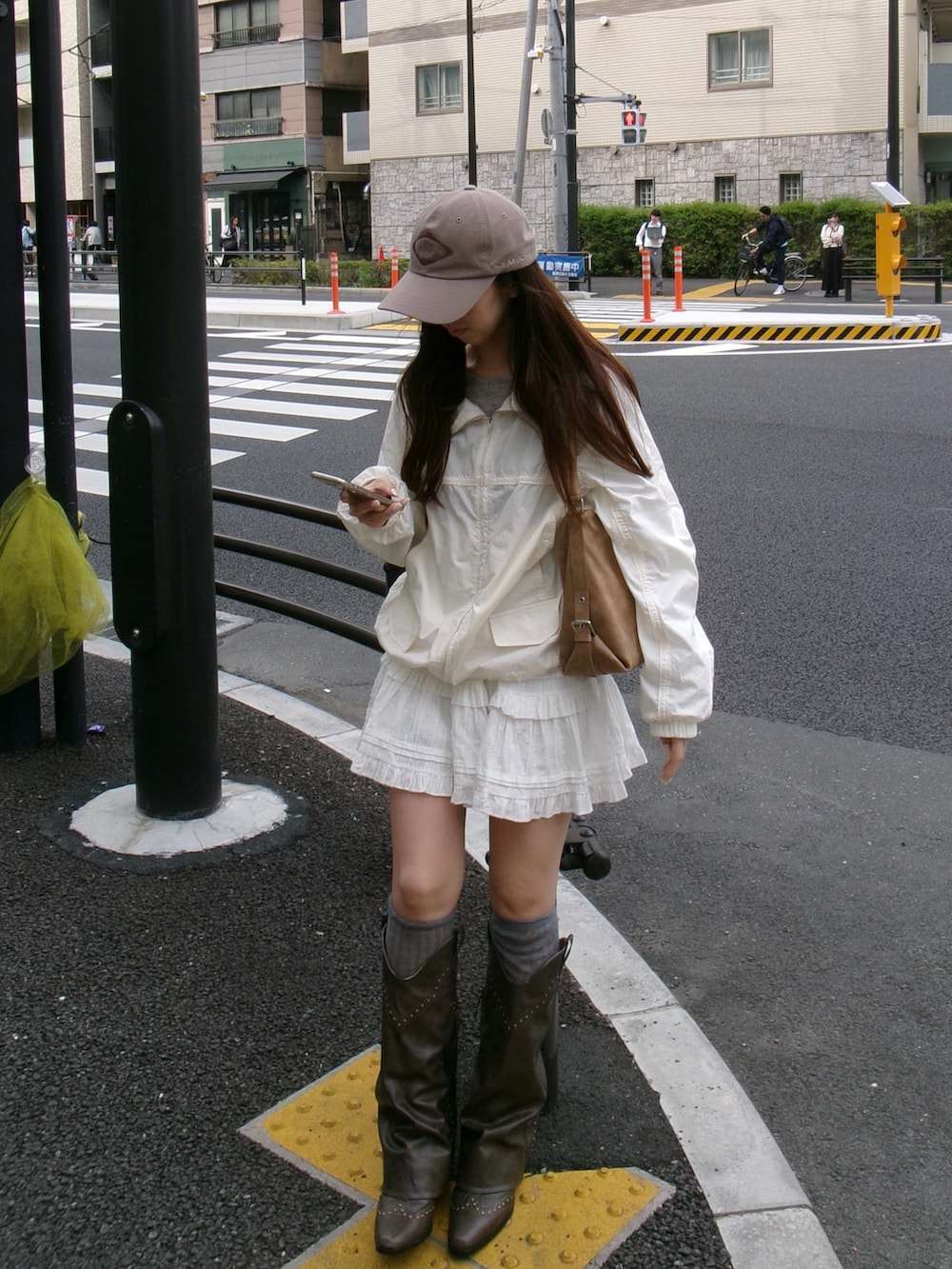 ブラウン系のブーツ、ベージュ系のバッグ、ホワイト系のジャケット/アウターを着用したレディースの春コーディネートの2枚目の写真