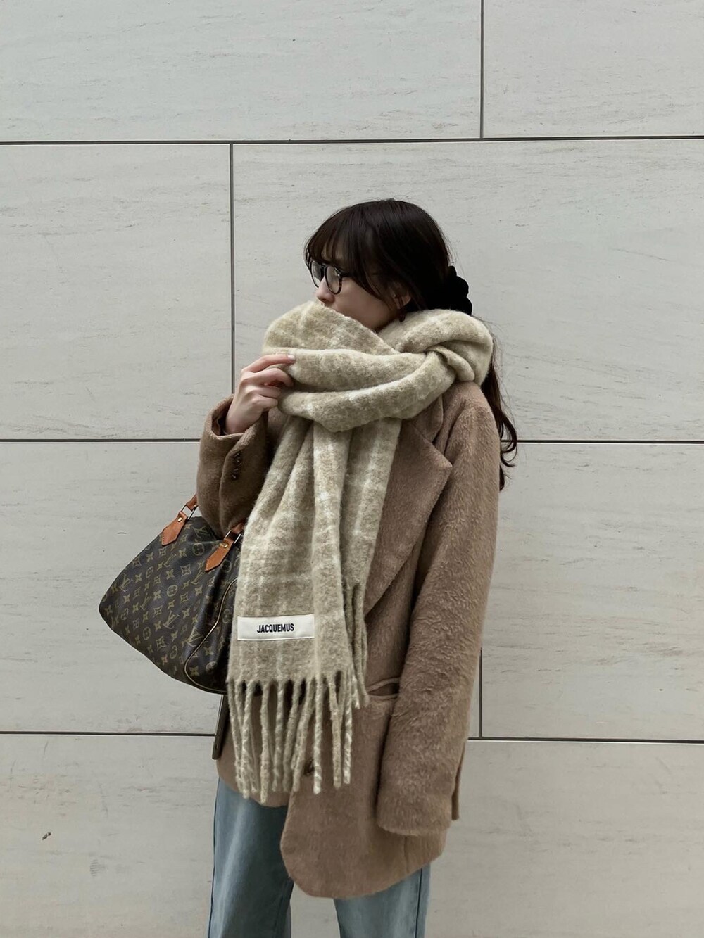 ブルー系のデニムパンツ、ブラウン系のスニーカー、ベージュ系のマフラーを着用したレディースの春コーディネートの2枚目の写真
