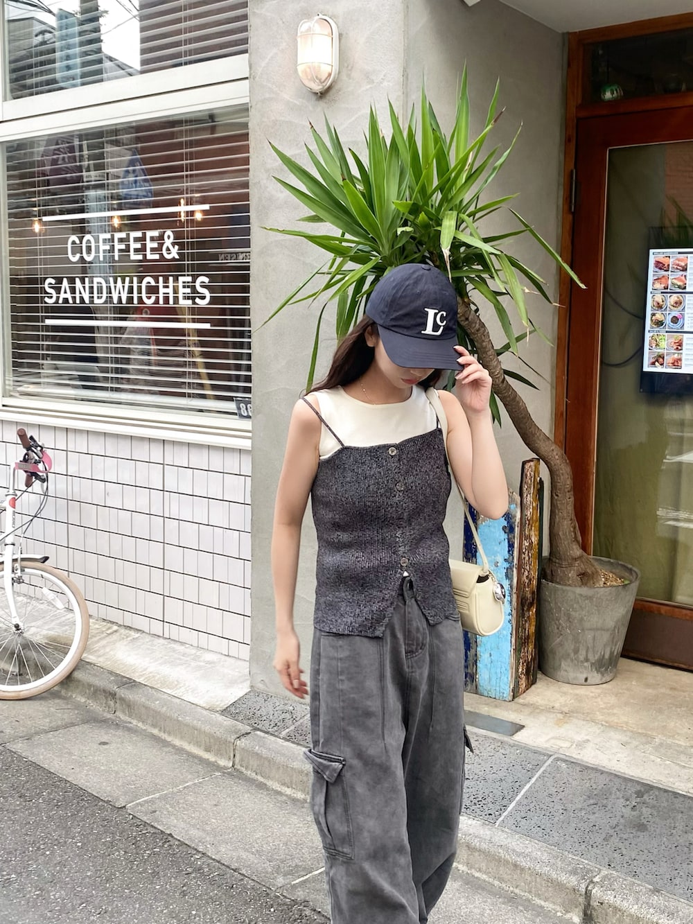 ホワイト系のニット/セーター、ブラック系のアンサンブル、ブラック系のデニムパンツを着用したレディースの秋コーディネートの3枚目の写真