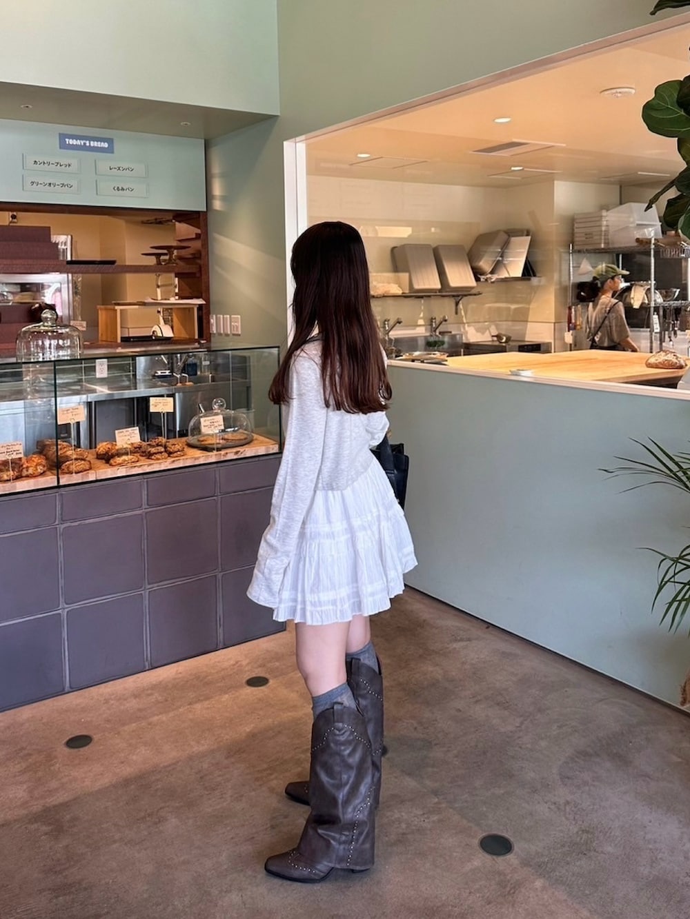 グレー系のTシャツ/カットソー、ホワイト系のスカート、ブラウン系のブーツを着用したレディースの秋コーディネートの2枚目の写真