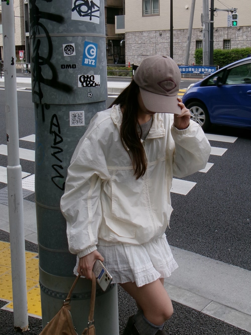 ブラウン系のブーツ、ベージュ系のバッグ、ホワイト系のジャケット/アウターを着用したレディースの春コーディネートの3枚目の写真