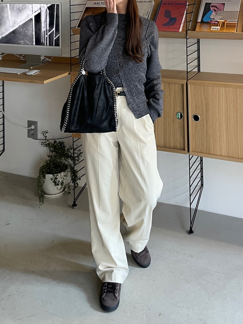 ブラック系のアンサンブル、ベージュ系のスラックス、ブラウン系のスニーカーを着用したレディースの冬コーディネートの2枚目の写真