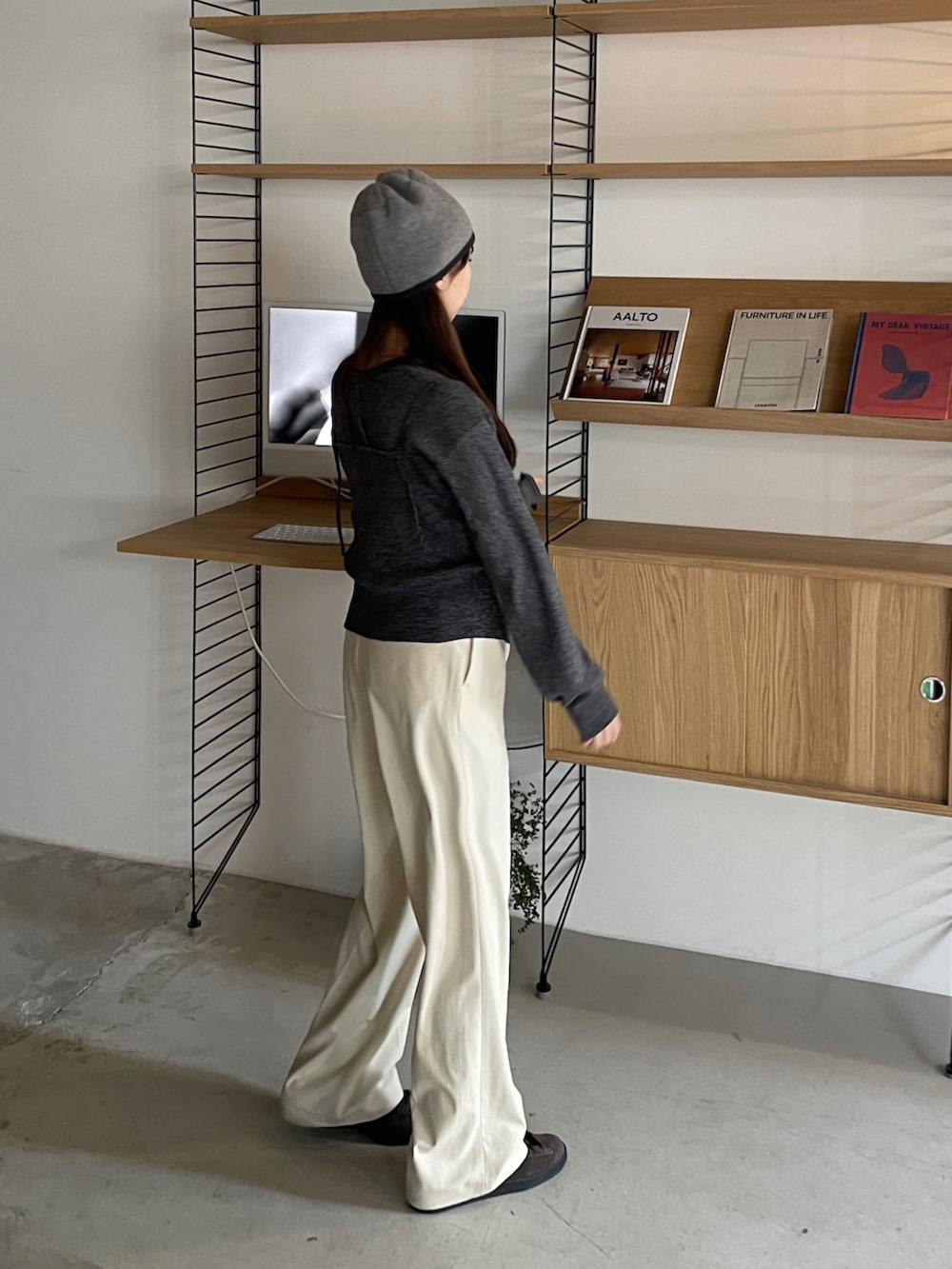 ブラック系のアンサンブル、ベージュ系のスラックス、ブラウン系のスニーカーを着用したレディースの冬コーディネートの3枚目の写真