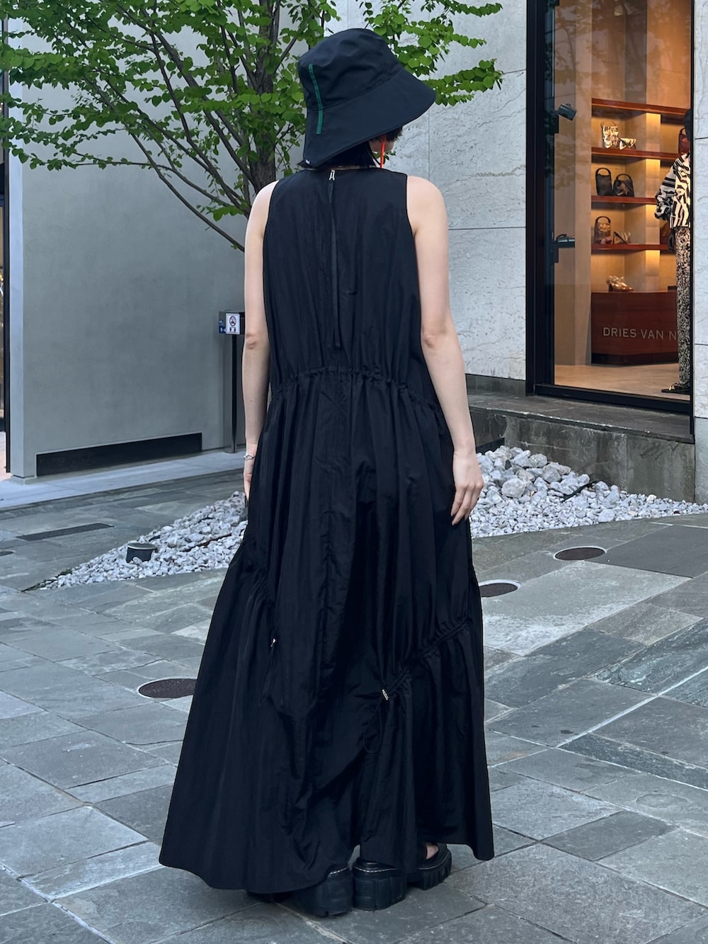 ブラック系のワンピース、ブラック系のサンダル、ブラック系のハットを着用したレディースの春コーディネートの3枚目の写真