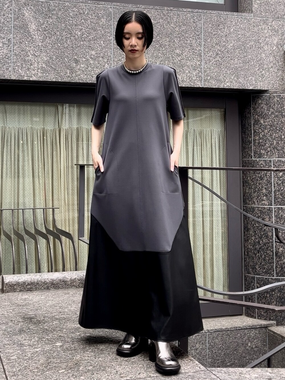 グレー系のワンピース、シルバー系のブーツ、シルバー系のネックレスを着用したレディースの夏コーディネートの2枚目の写真