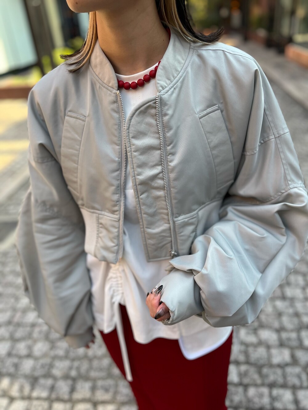 グレー系のMA-1、ホワイト系のTシャツ/カットソー、レッド系のスカートを着用したレディースの秋コーディネートの4枚目の写真