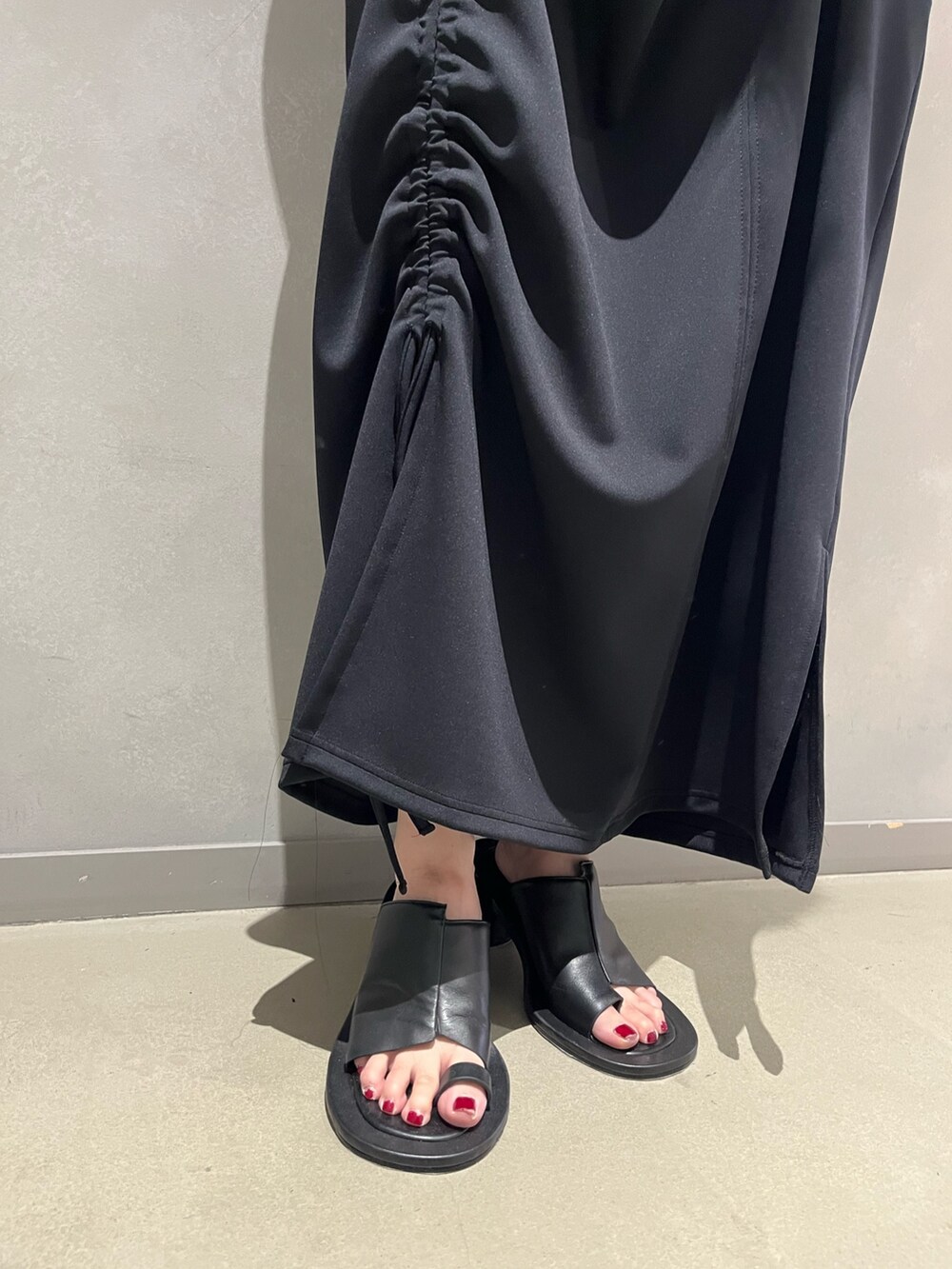 ブラック系のワンピース、ブラック系のサンダル、イエロー系のトートバッグを着用したレディースの夏コーディネートの7枚目の写真