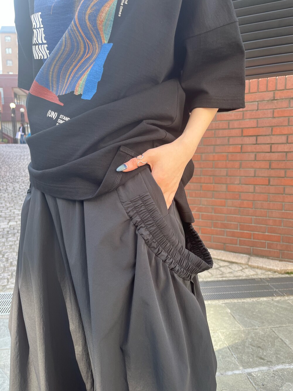 ブラック系のTシャツ/カットソー、ブラック系のその他パンツ、シルバー系のサンダルを着用したレディースの春コーディネートの10枚目の写真