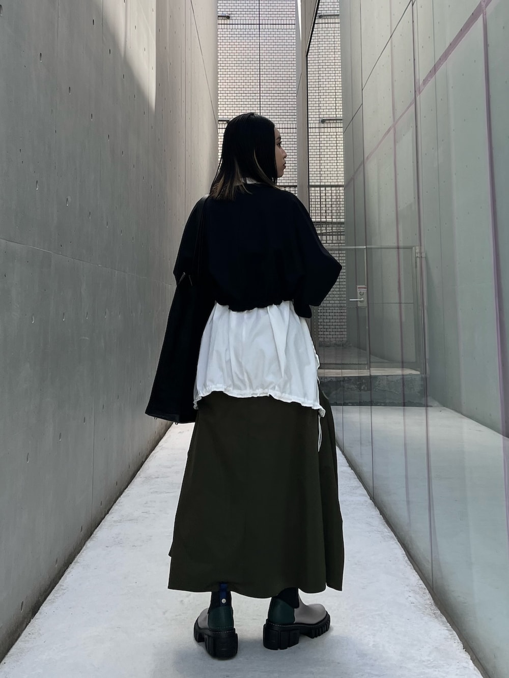 ブラック系のTシャツ/カットソー、ホワイト系のシャツ/ブラウス、グリーン系のスカートを着用したレディースの秋コーディネートの4枚目の写真