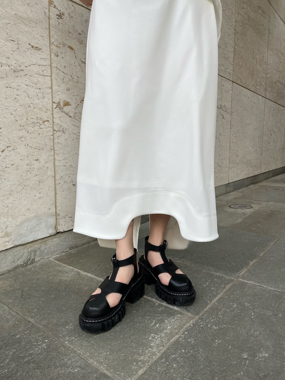 ホワイト系のワンピース、ブラック系のサンダル、ブラック系のイヤリングを着用したレディースの冬コーディネートの6枚目の写真