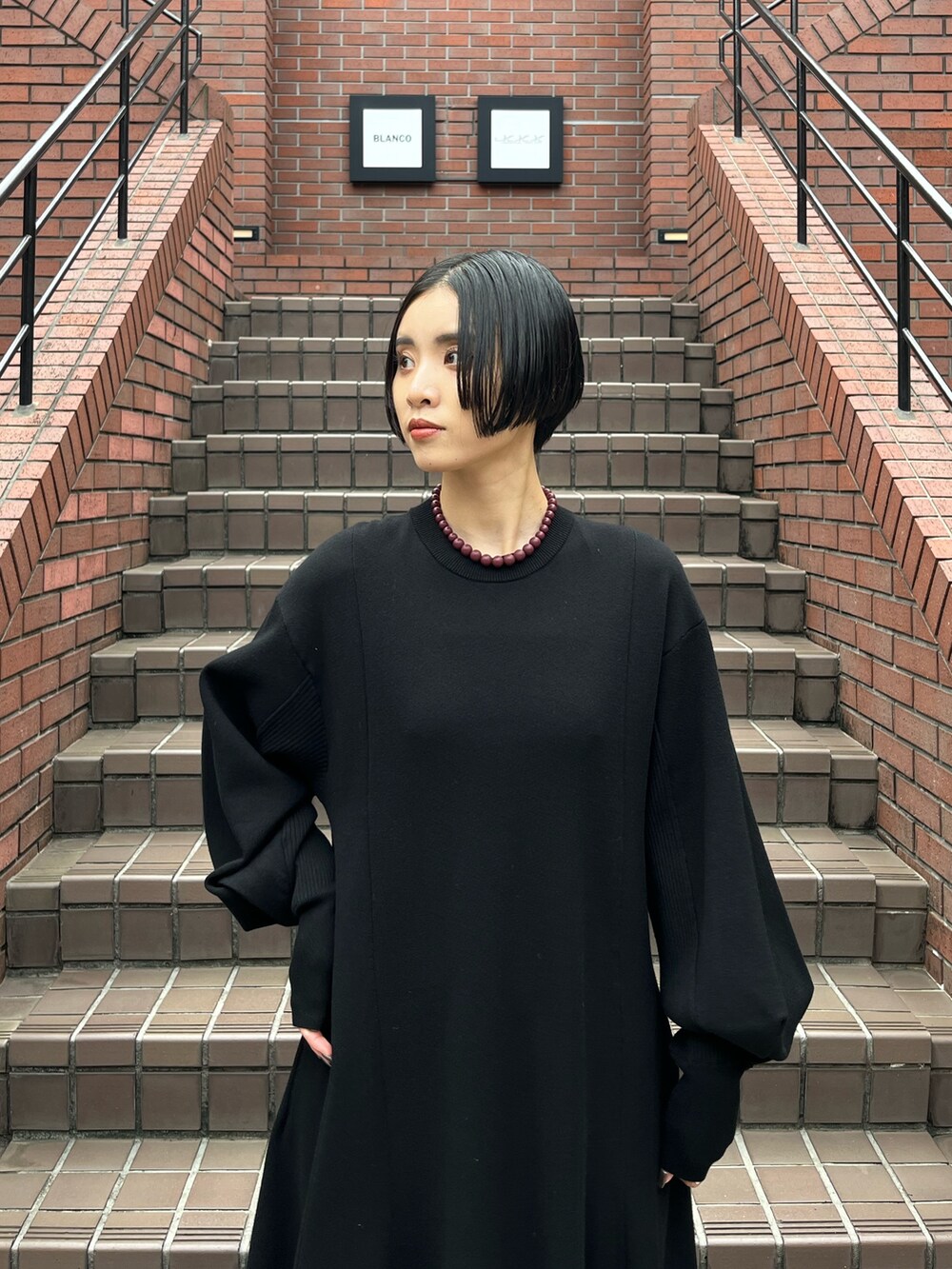 ブラック系のワンピース、シルバー系のブーツ、ブラウン系のネックレスを着用したレディースの秋コーディネートの5枚目の写真