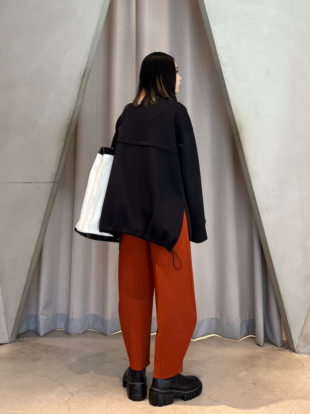 ブラック系のスウェット、オレンジ系のその他パンツ、ブラック系のブーツを着用したレディースの秋コーディネートの3枚目の写真