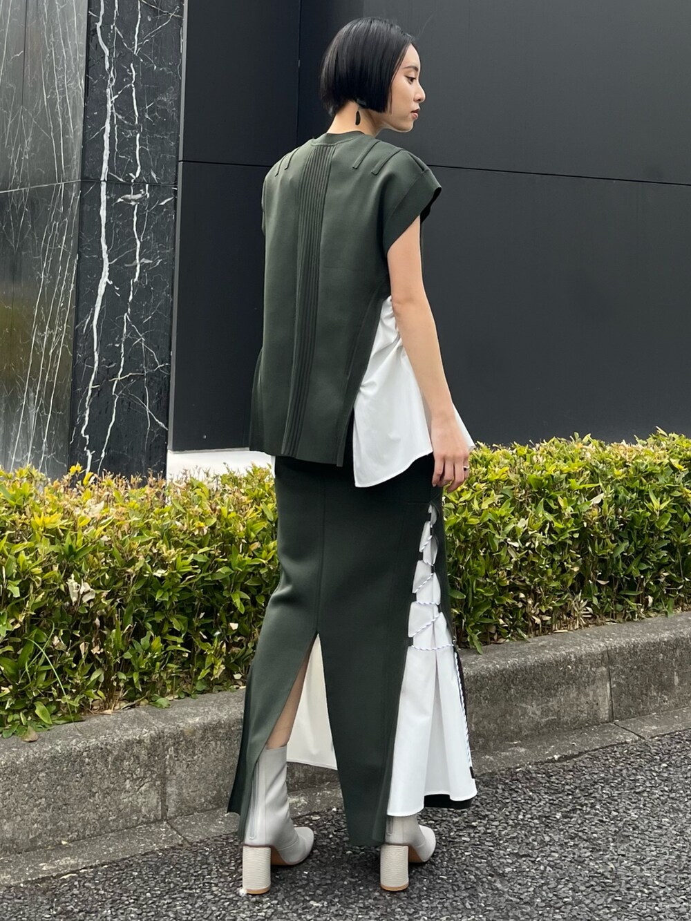 グリーン系のニット/セーター、グリーン系のスカート、ベージュ系のブーツを着用したレディースの春コーディネートの4枚目の写真