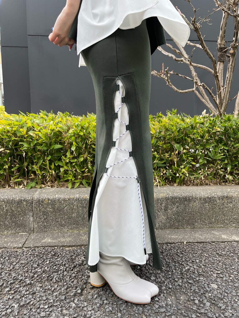 グリーン系のニット/セーター、グリーン系のスカート、ベージュ系のブーツを着用したレディースの春コーディネートの8枚目の写真