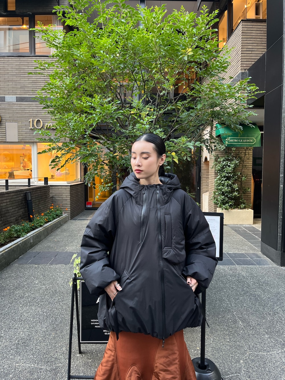 ブラック系のダウンジャケット/コート、イエロー系のスカート、ベージュ系のブーツを着用したレディースの秋コーディネートの3枚目の写真