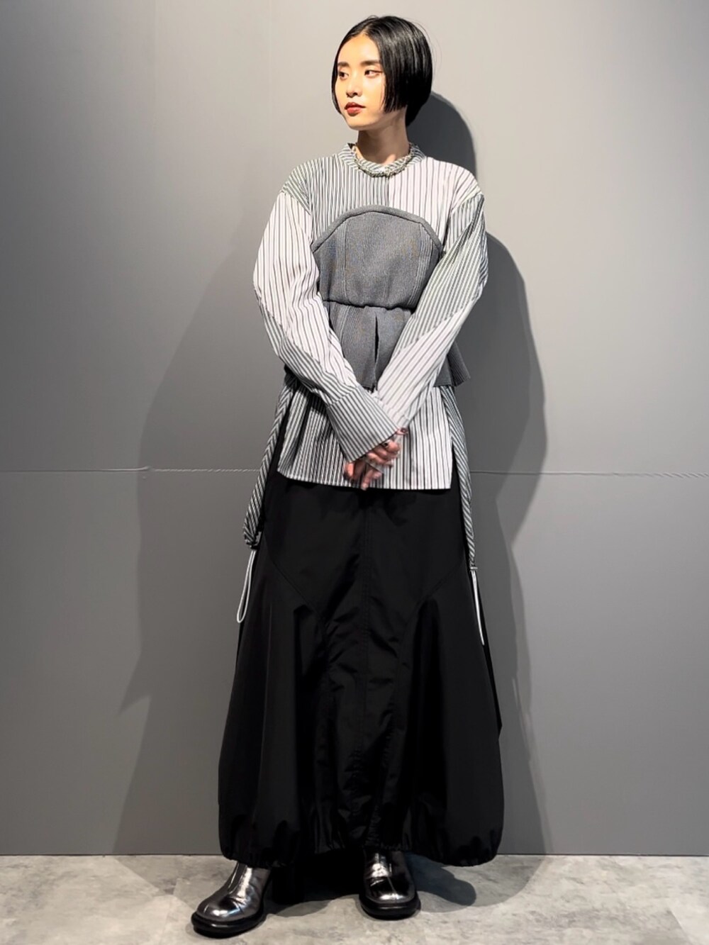 グレー系のシャツ/ブラウス、ブラック系のスカート、シルバー系のブーツを着用したレディースの秋コーディネートの2枚目の写真