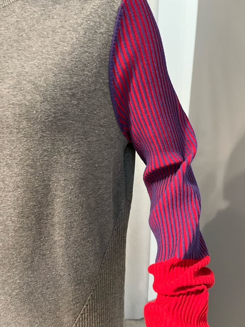 グレー系のワンピース、ブラック系のブーツ、ブラック系のマフラーを着用したレディースの秋コーディネートの7枚目の写真