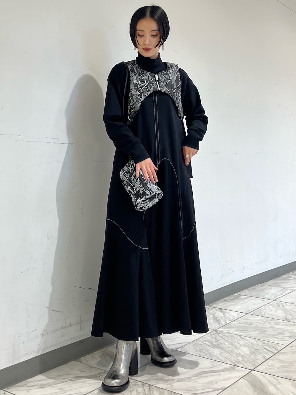 ブラック系のワンピース、ブラック系のベスト、シルバー系のブーツを着用したレディースの秋コーディネートの3枚目の写真