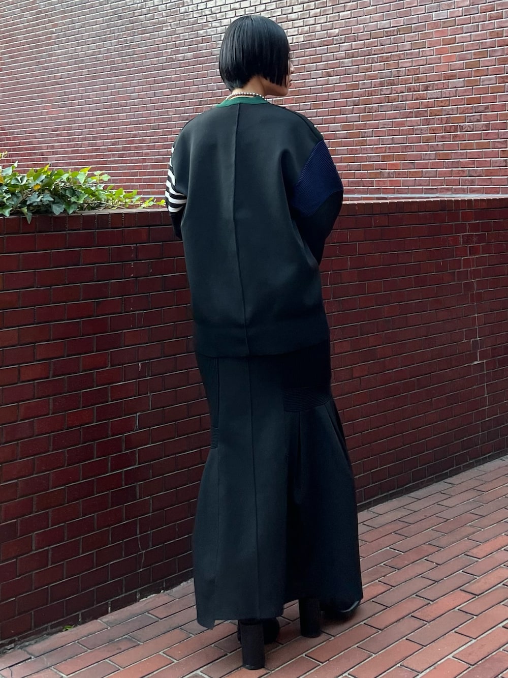 ブラック系のニット/セーター、ブラック系のスカート、ブラック系のブーツを着用したレディースの冬コーディネートの4枚目の写真