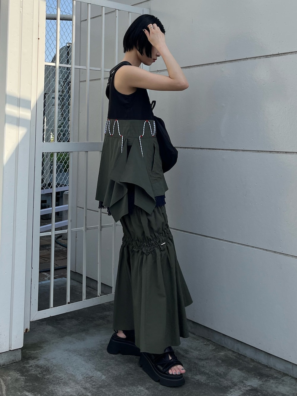 その他のタンクトップ、グリーン系のスカート、ブラック系のボディバッグ/ウエストポーチを着用したレディースの春コーディネートの2枚目の写真