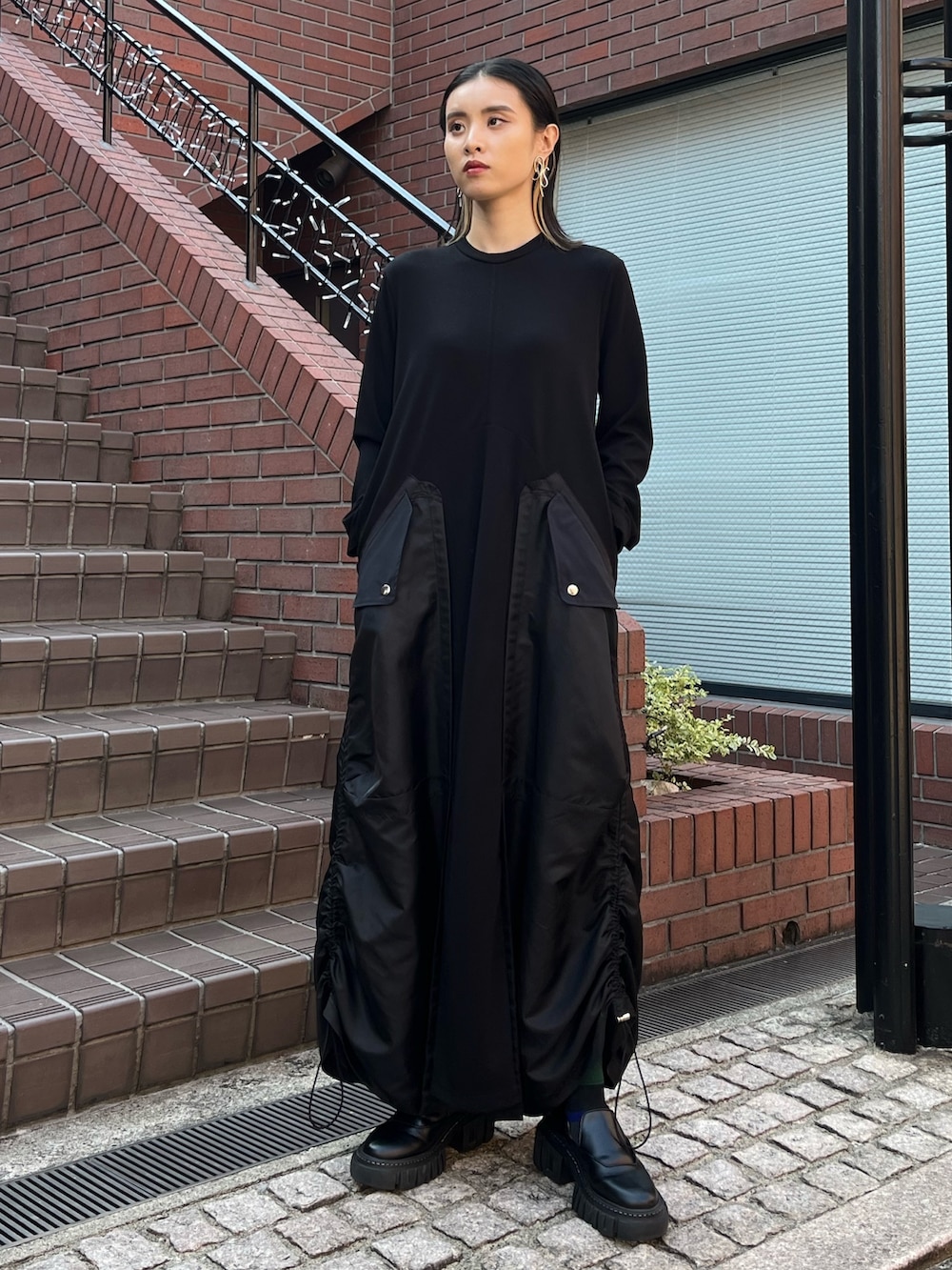 ブラック系のワンピース、ブラック系のローファー、シルバー系のイヤリングを着用したレディースの秋コーディネートの2枚目の写真