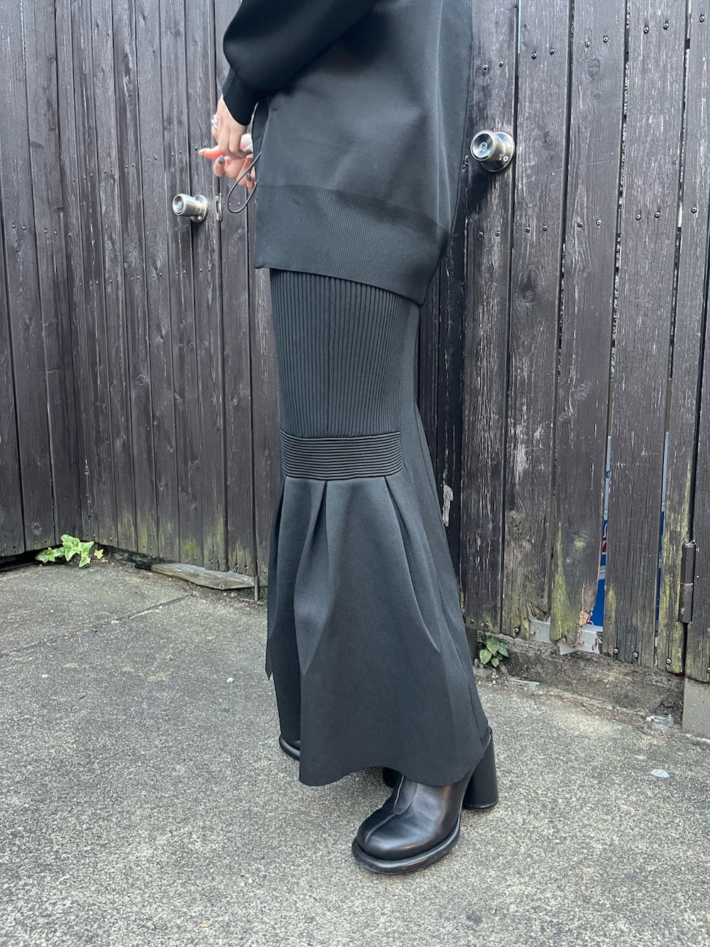 ブラック系のニット/セーター、ブラック系のスカート、ブラック系のブーツを着用したレディースの冬コーディネートの7枚目の写真