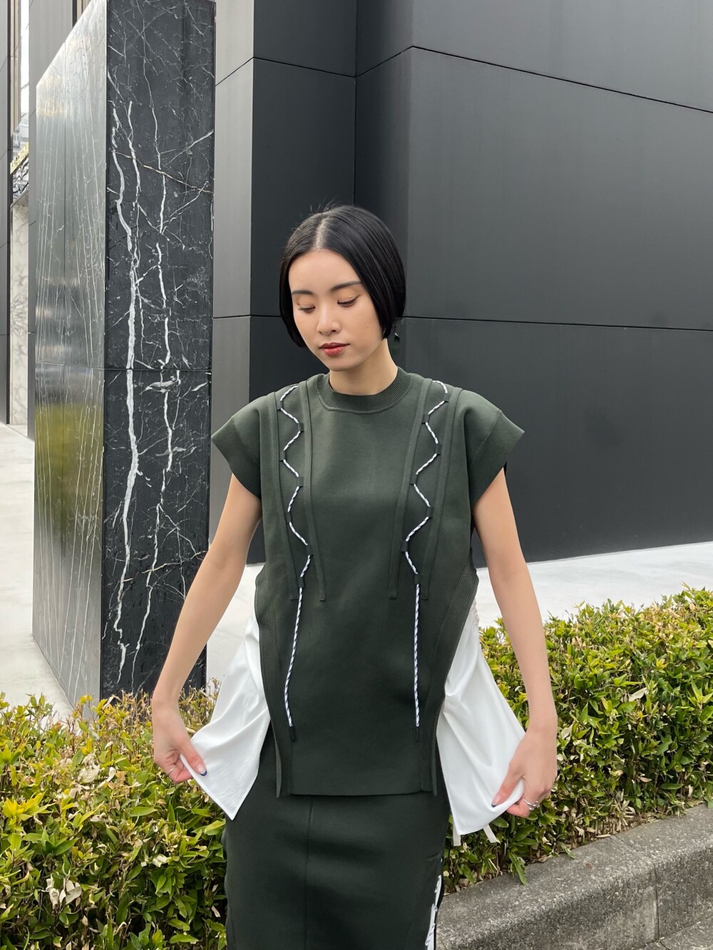 グリーン系のニット/セーター、グリーン系のスカート、ベージュ系のブーツを着用したレディースの春コーディネートの6枚目の写真