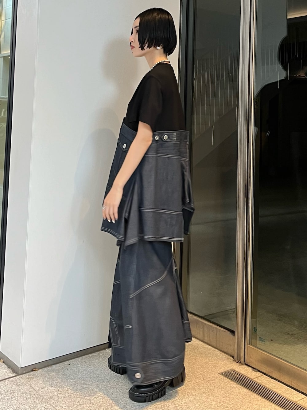 ブルー系のスカート、ブルー系のTシャツ/カットソー、ブラック系のブーツを着用したレディースの冬コーディネートの2枚目の写真